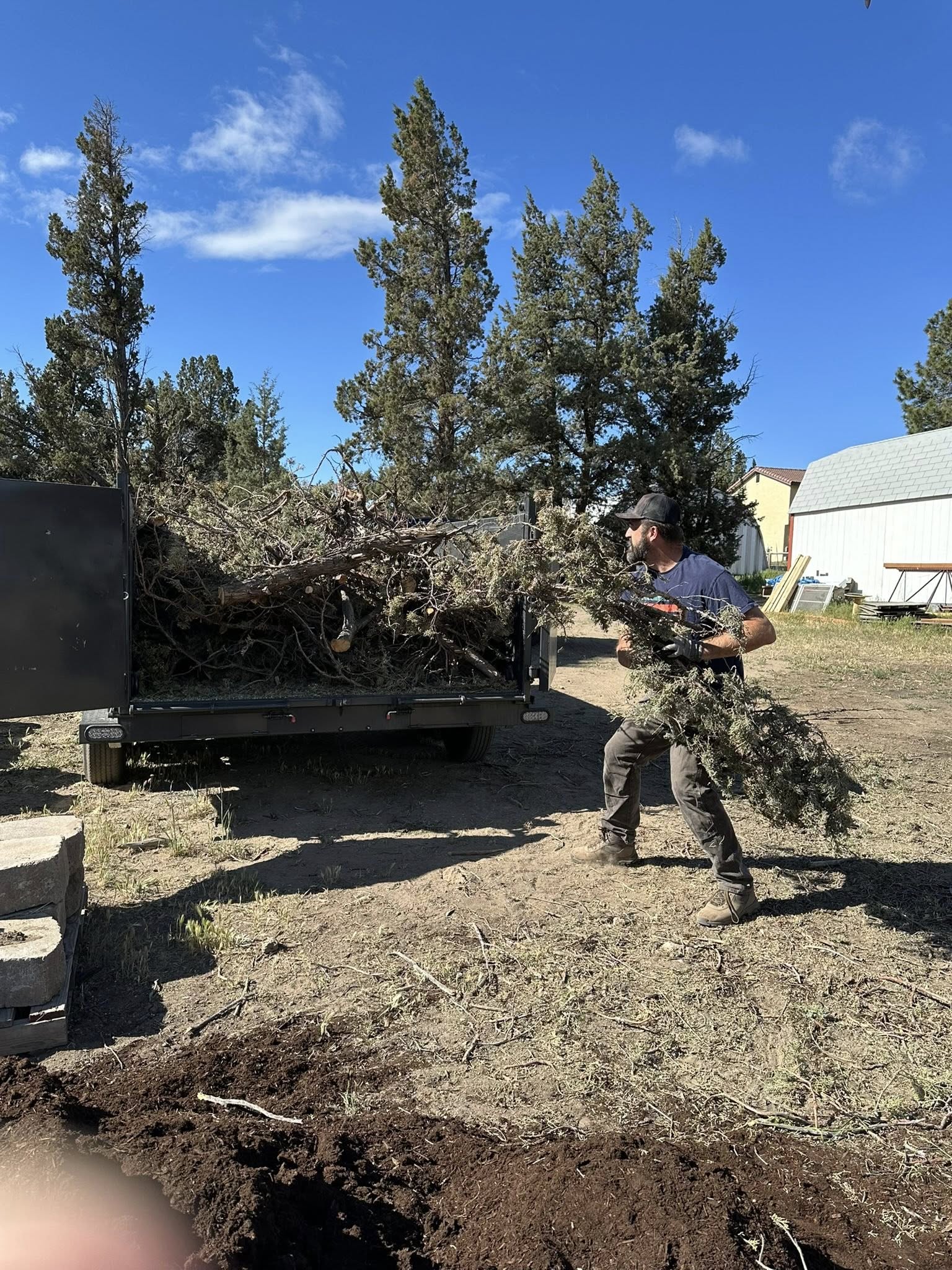 Loading brush and yard debris into the High Desert Hauling dump trailer